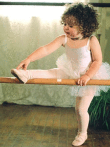 Girl in a tutu with her leg on a ballet bar.