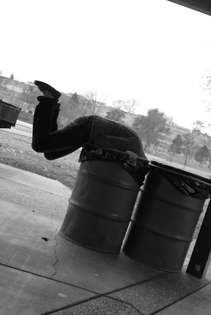 man in garbage can digging for coupons