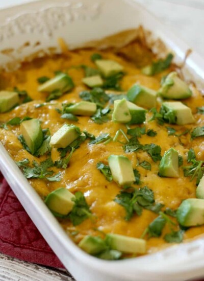 Enchilada casserole topped with avocado in a baking dish.