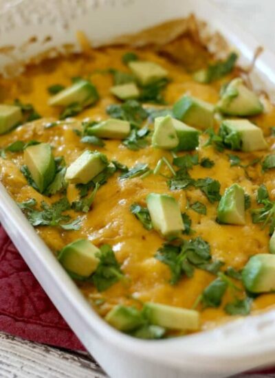 Enchilada casserole topped with avocado in a baking dish.