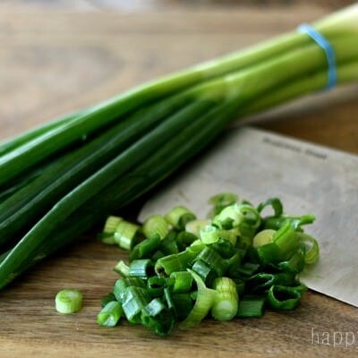Chopped green onions with a knife and whole green onions.