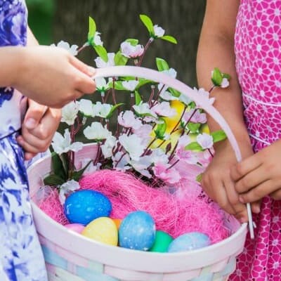 Two kids in bright dresses holding an Easter basket.