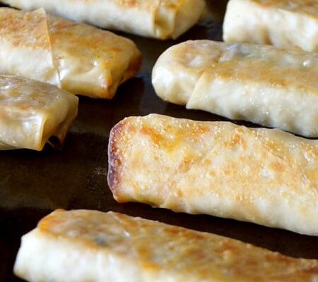 Baked egg rolls on a baking sheet.