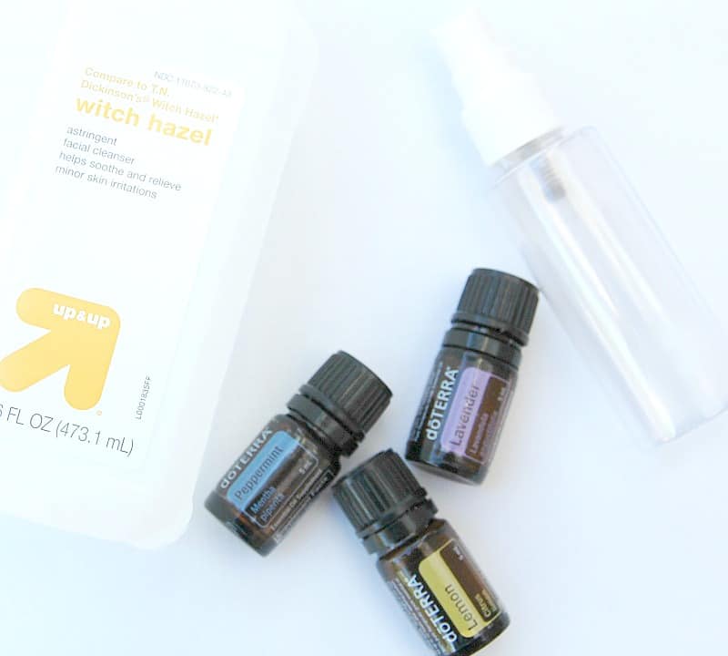 Empty spray bottle with bottles of doTerra essential oils and a bottle of witch hazel.