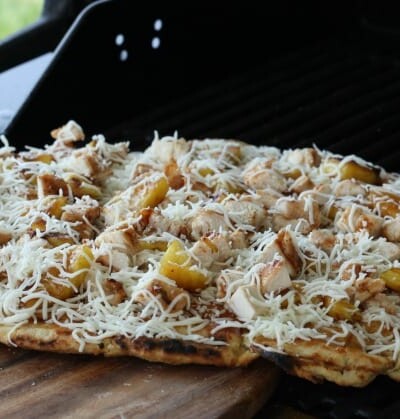 Grilled Hawaiian barbeque pizza on a wooden board.