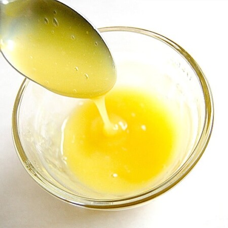 Orange glaze running from a spoon into a small bowl.