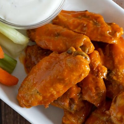 Chicken wings and vegetables on a plate with dip.
