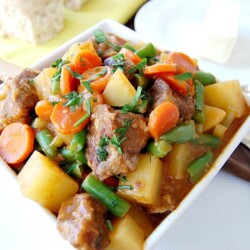 Beef stew in a white, square bowl.