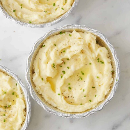Make Ahead Mashed Potatoes with herbs and butter on top 3 in a foil pan