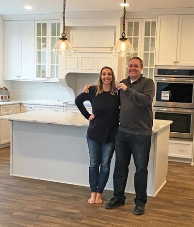 Two people smiling in a clean, white kitchen.