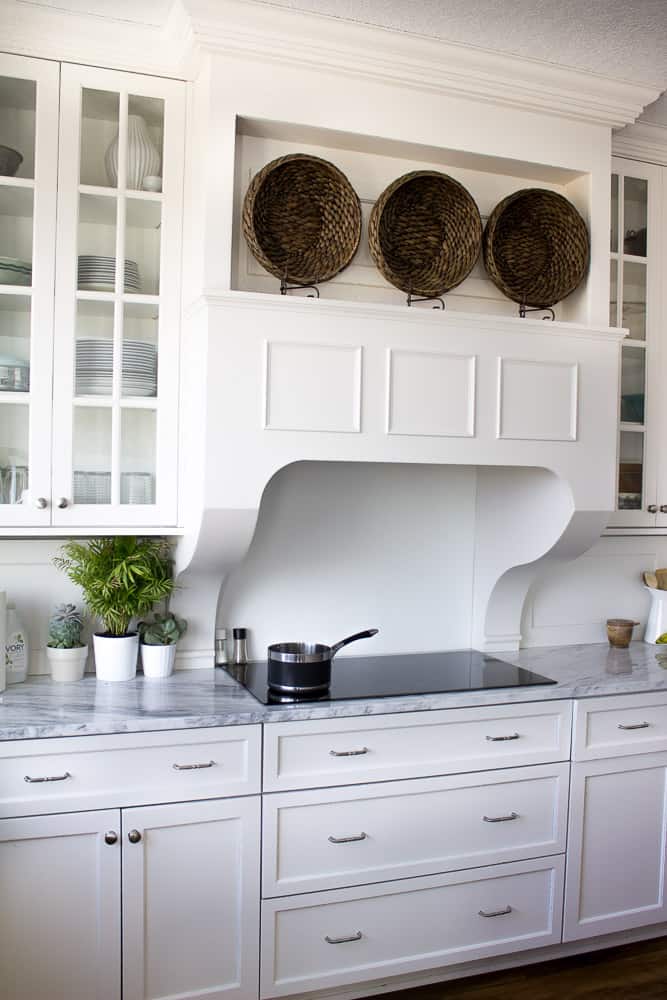 Gorgeous white kitchen with induction cooktop. Custom hood and white quartzite countertops.