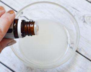 Person adding essential oil to a small bowl.
