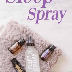 Essential oils and a spray bottle on a soft towel.