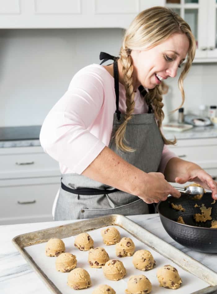 Karrie scooping cookie dough onto a lined baking sheet.