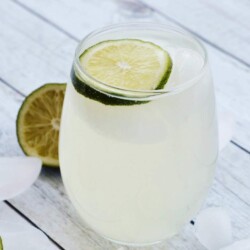 Glass of sparkling ginger limeade topped with a lime slice.