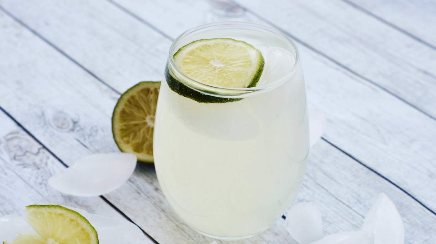 Glass of sparkling ginger limeade topped with a lime slice.