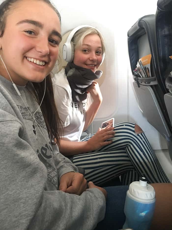 Two people in airplane seats smiling.