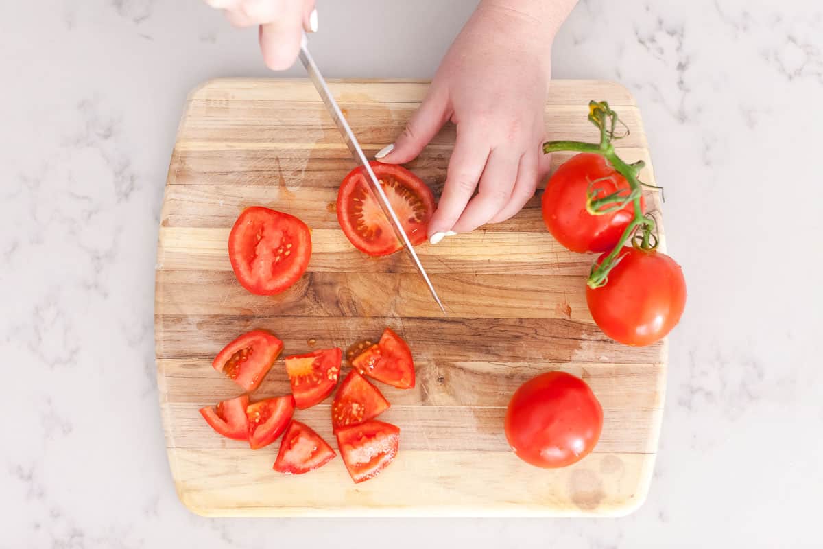 cutting fresh tomatoes on cutting board