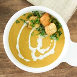 Bowl of cashew butternut squash soup topped with croutons.