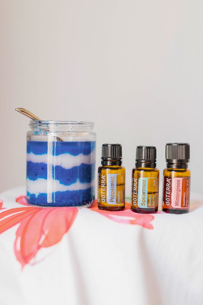 Bottles of doTerra essential oils with a jar of blue and white sugar scrub.