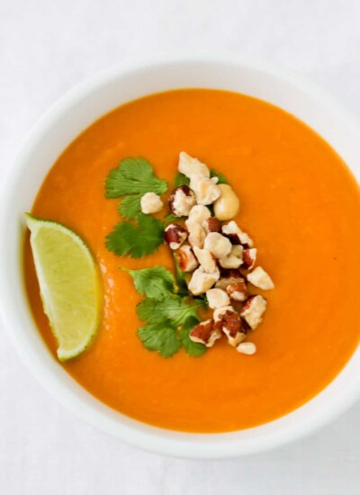 Bowl of Thai yam soup topped with nuts and a lime wedge.