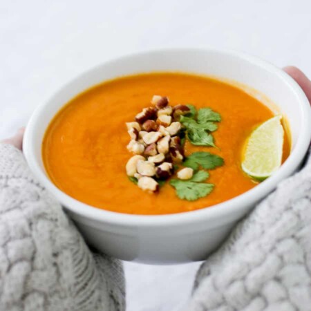 Bowl of Thai yam soup topped with nuts and a lime wedge.