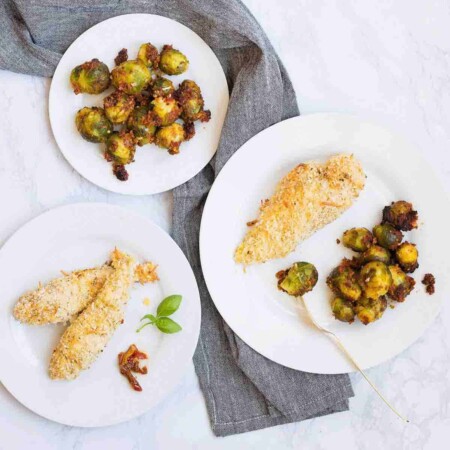 Plates of cheesy crunch chicken and Italian brussels sprouts.