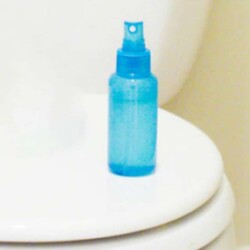 Blue spray bottle sitting on a toilet.