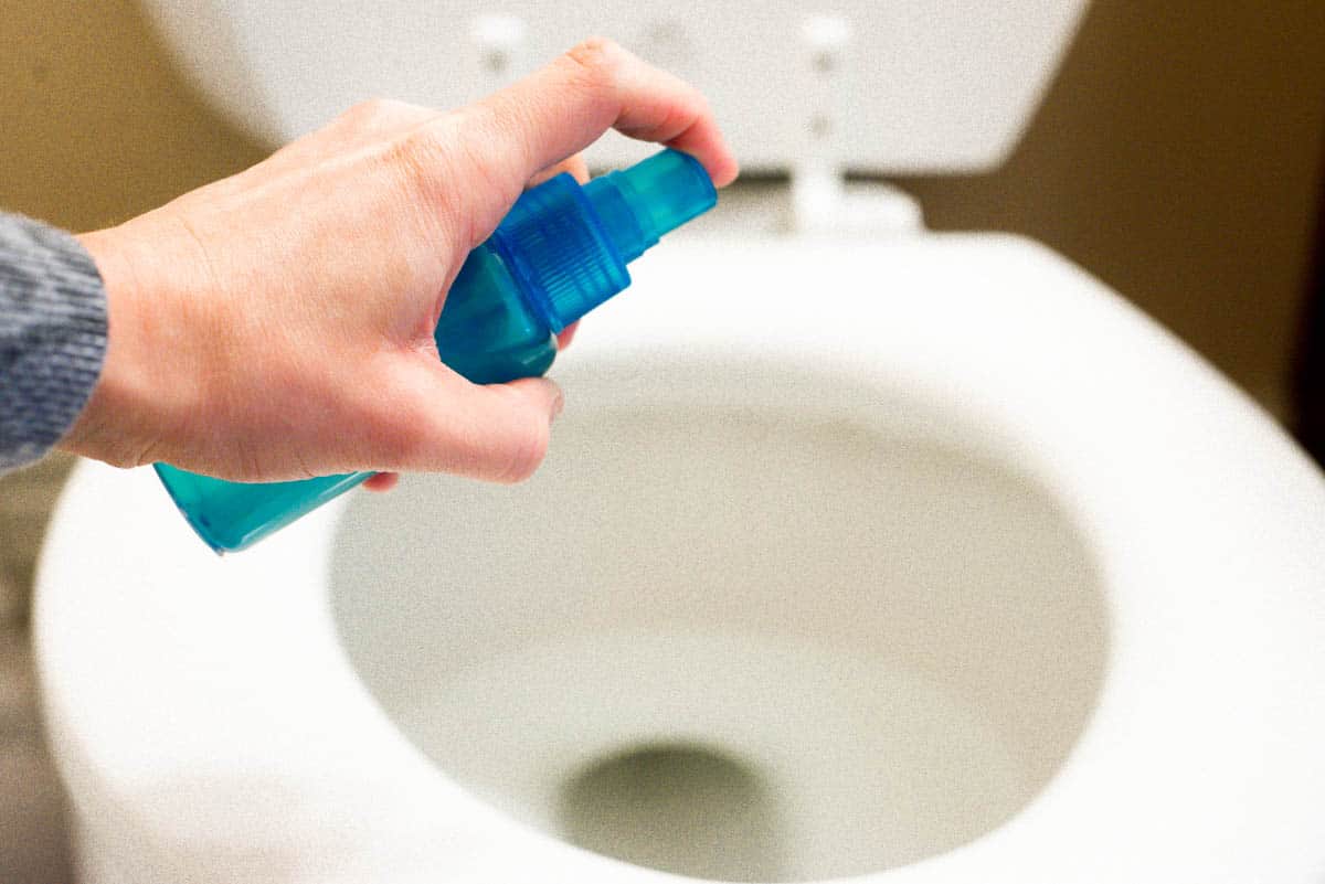 spraying homemade poo pourri spray into toilet
