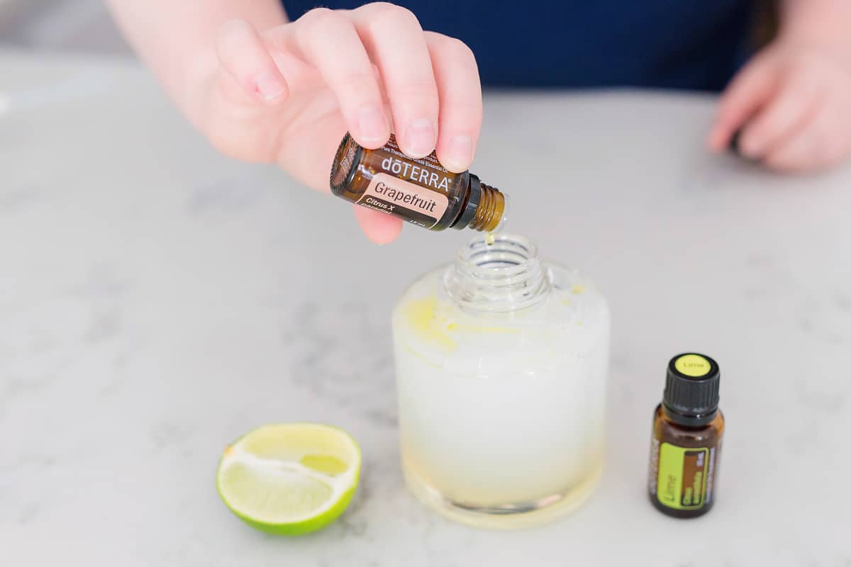 A hand pouring doterra grapefruit essential oil being made into homemade liquid hand soap.