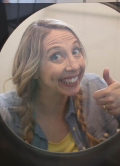 Karrie smiling and giving a thumbs up through the window of her Maytag washer.