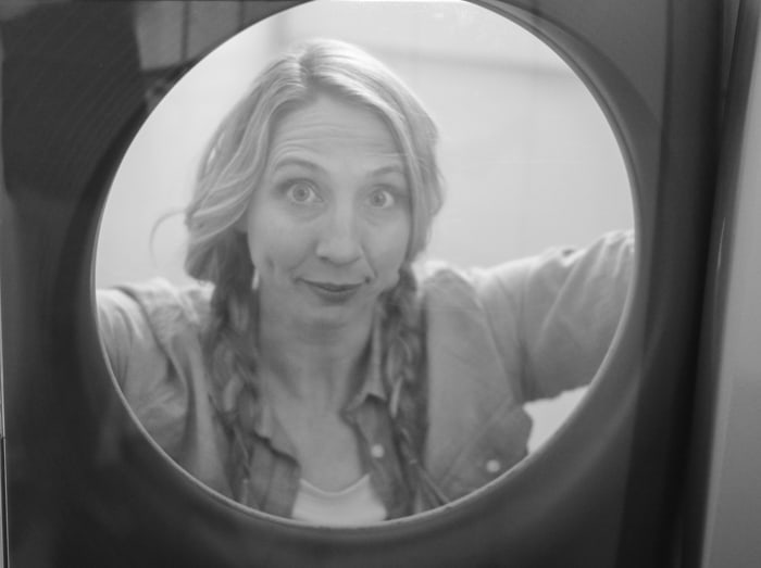 Black and white photo of Karrie through the window of her Maytag washer.