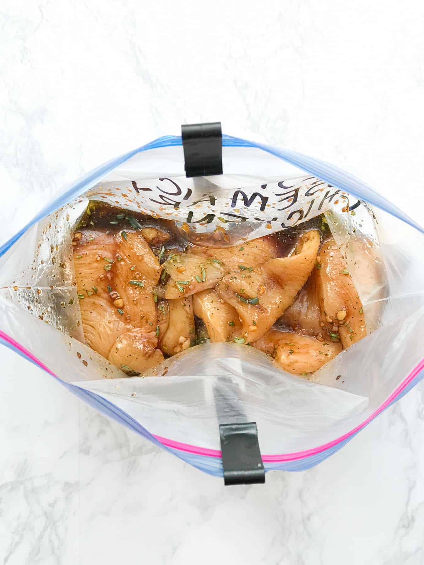 Balsamic Rosemary Chicken freezer meal in a bag holder inside a freezer bag.