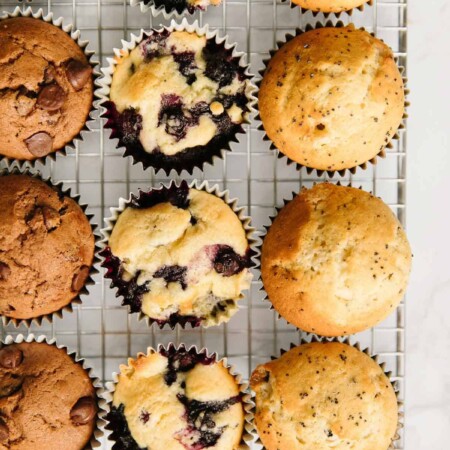 Different-flavored muffins on a wire rack.