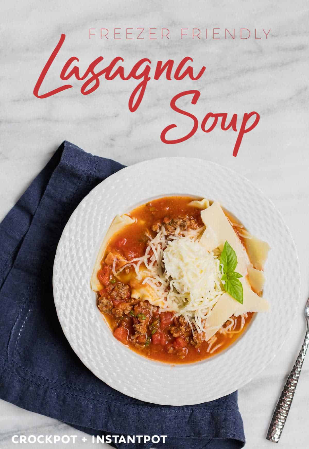 A white bowl is lasagna soup topped with cheese and sprig of herbs with a blue napkin underneath and a silver fork on the side. The words "Freezer Friendly Lasagna Soup" are at the top and "Crockpot + InstantPot" are at the bottom.