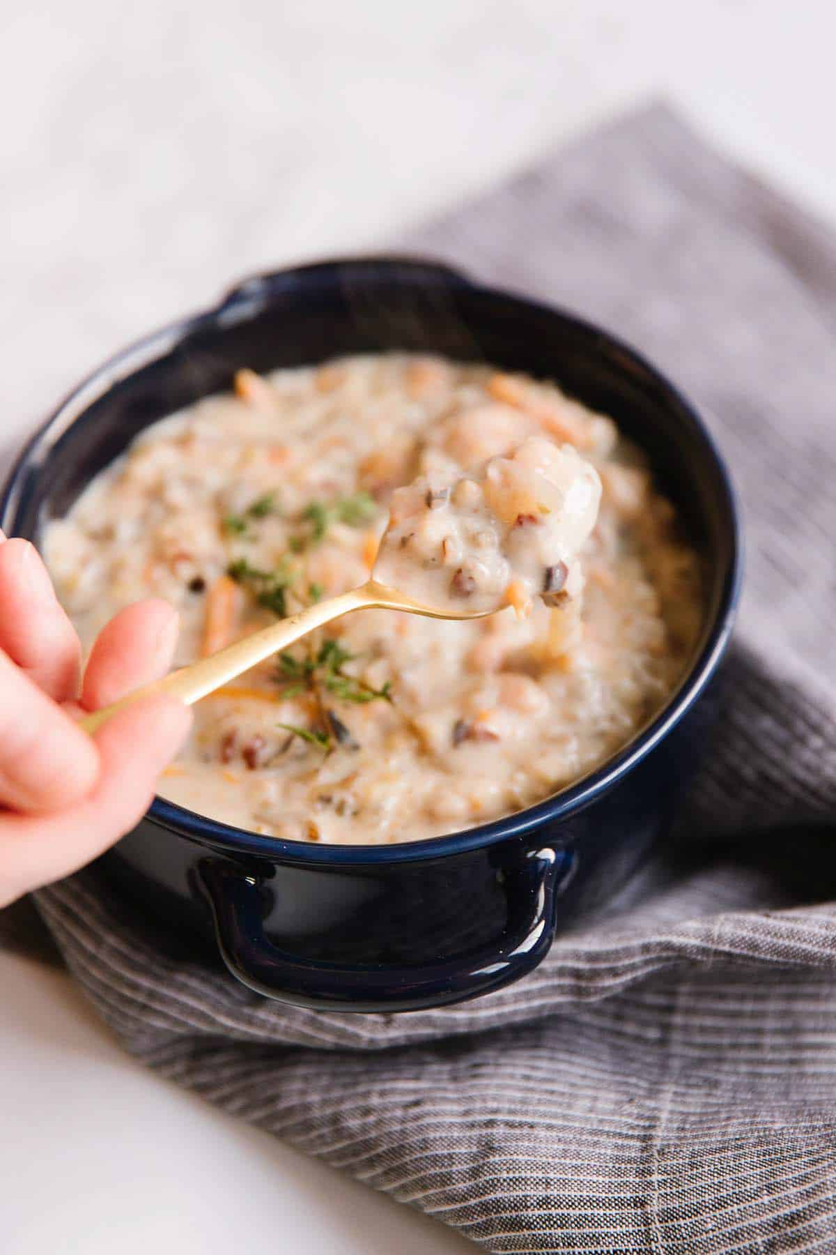 Creamy chicken and wild rice soup in a navy bowl with a golden spoon