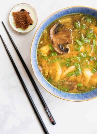 Bowl of miso soup next to black chopsticks.