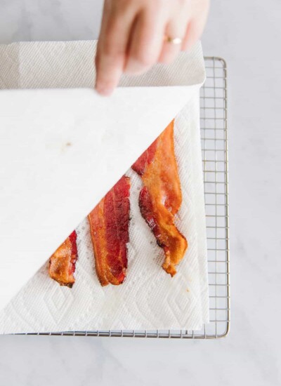 Person putting paper towel over bacon.