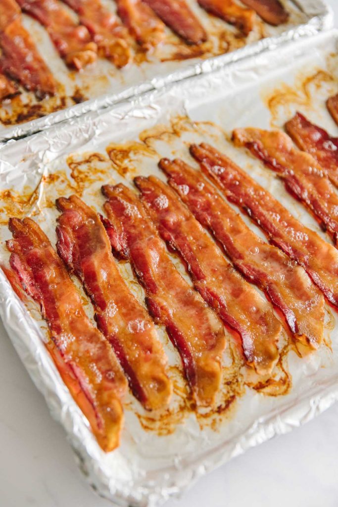 Strips of bacon on two foil-wrapped pans at a diagonal.