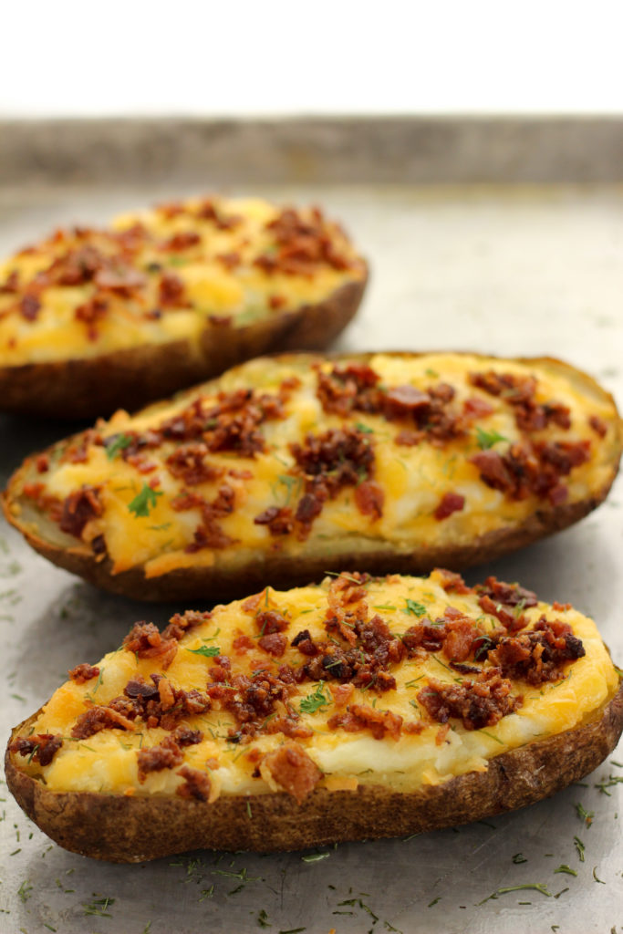 3 twice baked potatoes with bacon and dill on top.  Dill is sprinkled on the floor.