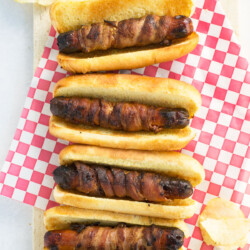 Three bacon-wrapped hot dogs on buns.