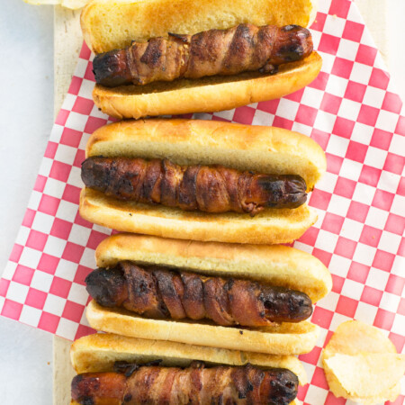 Three bacon-wrapped hot dogs on buns.