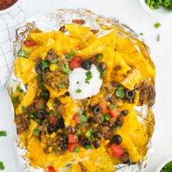 Foil packet of nachos topped with sour cream.