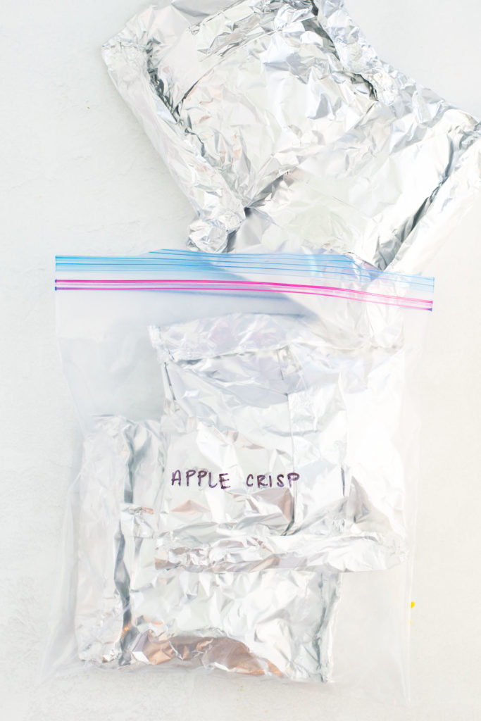 A gallon size zippered bag with four foil packets - two inside the bag and two outside the bag.  On the bag is written Apple Crisp on it with black marker.