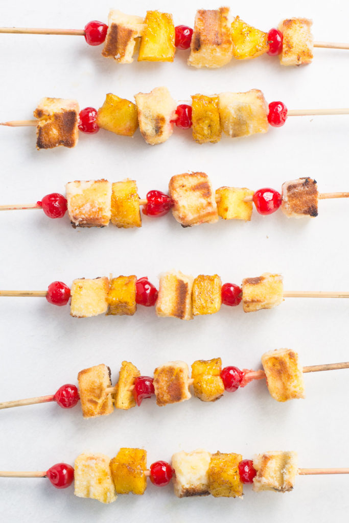 6 pineapple upside cake campfire dessert kabobs laying down on a white background.