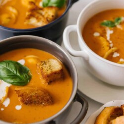 Bowls of creamy tomato basil soup topped with croutons.