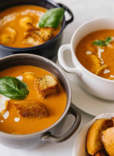 Bowls of creamy tomato basil soup topped with croutons.