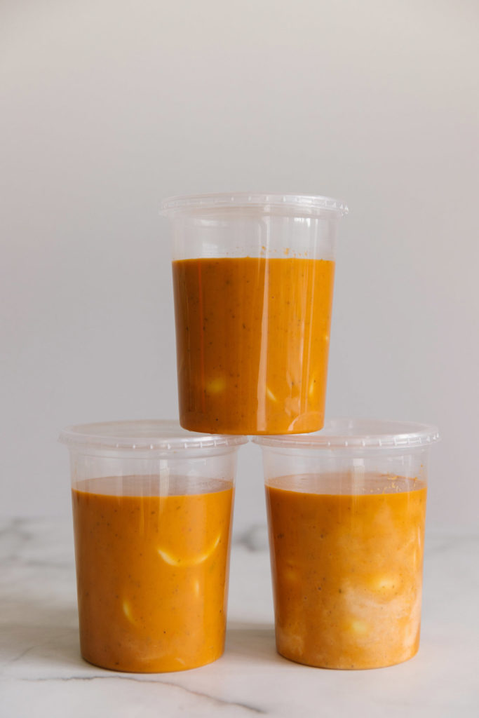 Three plastic 32 oz containers of creamy tomato basil soup with ravioli. 