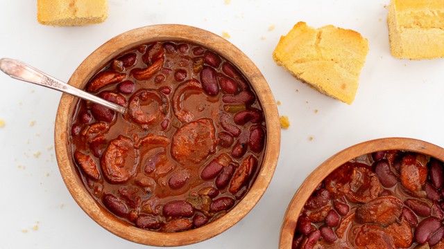 Simple chili with smoked sausage and red kidney beans in wooden bowl and a few squares of cornbread  