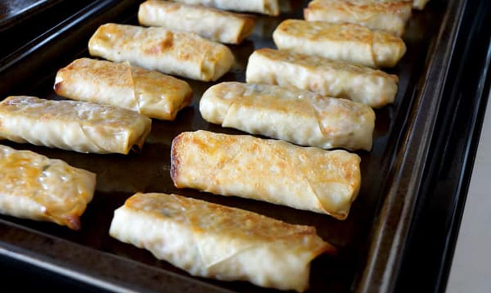 several cooked eggrolls on a baking sheet 